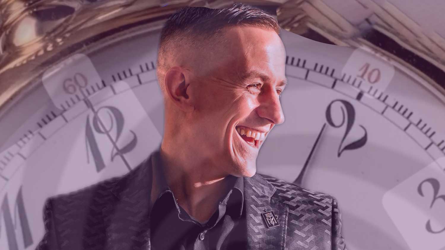 A smiling man with a picture of a huge fob watch in the background